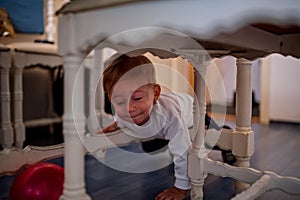 Adorable crawling baby boy under a table