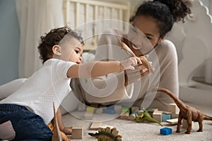 Adorable curious little mixed race baby playing toys with nanny.