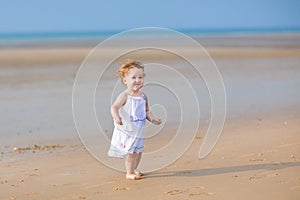 Adorable curly baby girl walking on beach