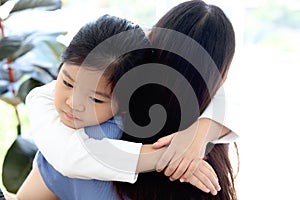 Adorable cute Asia girl daughter feeling sick and hugging her mom with love, warm love in family, mom taking care of sad kid has