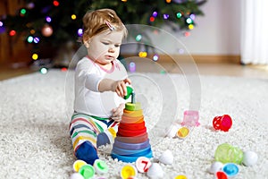 Adorable cute beautiful little baby girl playing with educational colorful wooden rainboy toy pyramid