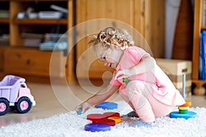 Adorable cute beautiful little baby girl playing with educational colorful wooden rainboy toy pyramid