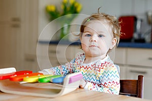 Adorable cute beautiful little baby girl playing with educational wooden music toy at home. Happy excited toddler child