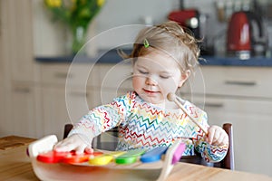 Adorable cute beautiful little baby girl playing with educational wooden music toy at home. Happy excited toddler child