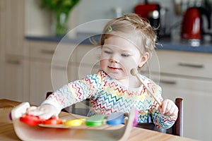 Adorable cute beautiful little baby girl playing with educational wooden music toy at home. Happy excited toddler child