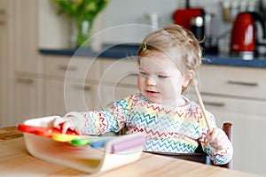 Adorable cute beautiful little baby girl playing with educational wooden music toy at home. Happy excited toddler child