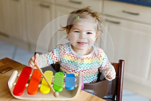 Adorable cute beautiful little baby girl playing with educational wooden music toys at home or nursery