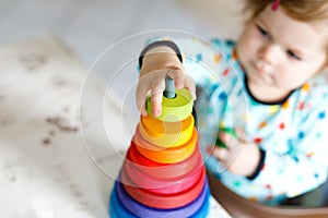 Adorable cute beautiful little baby girl playing with educational wooden rainbow toy pyramid