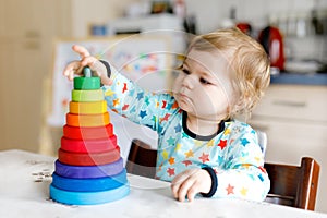 Adorable cute beautiful little baby girl playing with educational wooden rainbow toy pyramid