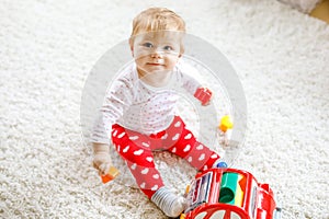 Adorable cute beautiful little baby girl playing with educational wooden toys at home or nursery. Healthy happy toddler