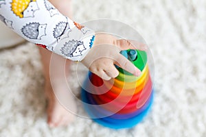 Adorable cute beautiful little baby girl playing with educational wooden toys at home or nursery. Toddler with colorful