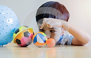 Adorable cute boy playing colorful balls with fun and happiness, playful laughing, smiling in living room at home on weekend