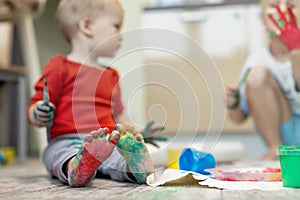 Adorable cute caucasian little blond siblings children enjoy having fun painting with brush and palm at home indoors