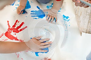 Adorable cute caucasian little blond siblings children enjoy having fun together with mother painting brush and palm at home