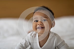 Adorable Cute Infant African American Baby Relaxing On Bed, Lying On His Tummy