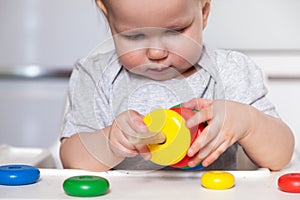 Adorable cute little baby is playing with colorful wooden pyramid