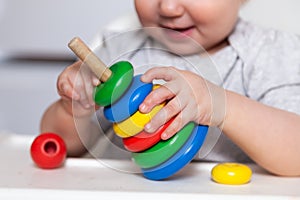 Adorable cute little baby is playing with colorful wooden pyramid. Focus on pyramid