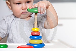 Adorable cute little baby is playing with colorful wooden pyramid. Focus on pyramid