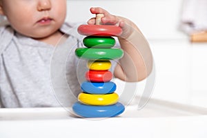 Adorable cute little baby is playing with colorful wooden pyramid. Focus on pyramid