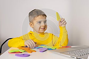 Adorable, cute, little boy learning alphabet online, with laptop at home. Child using e-learning platform to make a