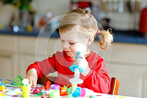 Adorable cute little toddler girl with colorful clay. Healthy baby child playing and creating toys from play dough