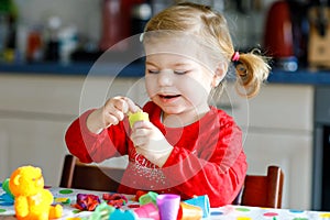 Adorable cute little toddler girl with colorful clay. Healthy baby child playing and creating toys from play dough