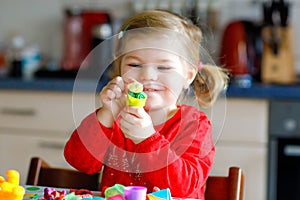 Adorable cute little toddler girl with colorful clay. Healthy baby child playing and creating toys from play dough