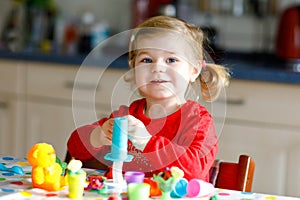 Adorable cute little toddler girl with colorful clay. Healthy baby child playing and creating toys from play dough