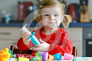 Adorable cute little toddler girl with colorful clay. Healthy baby child playing and creating toys from play dough