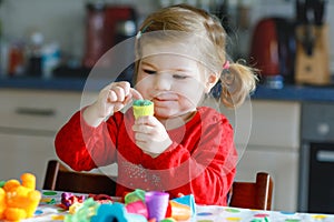 Adorable cute little toddler girl with colorful clay. Healthy baby child playing and creating toys from play dough
