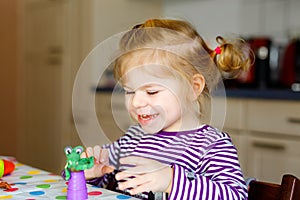 Adorable cute little toddler girl with colorful clay. Healthy baby playing and creating toys from play dough. Small kid