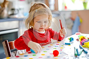 Adorable cute little toddler girl with colorful clay. Healthy baby playing and creating toys from play dough. Small kid