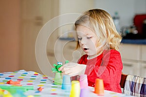 Adorable cute little toddler girl with colorful clay. Healthy baby playing and creating toys from play dough. Small kid