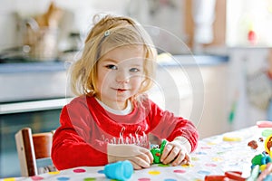 Adorable cute little toddler girl with colorful clay. Healthy baby playing and creating toys from play dough. Small kid