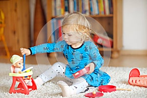 Adorable cute little toddler girl playing with doll. Happy healthy baby child having fun with role game, playing mother