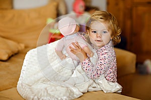 Adorable cute little toddler girl playing with doll. Happy healthy baby child having fun with role game, playing mother