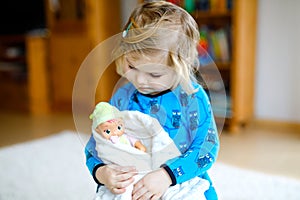 Adorable cute little toddler girl playing with doll. Happy healthy baby child having fun with role game, playing mother