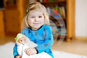 Adorable cute little toddler girl playing with doll. Happy healthy baby child having fun with role game, playing mother