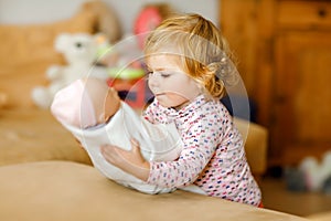 Adorable cute little toddler girl playing with doll. Happy healthy baby child having fun with role game, playing mother