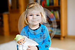 Adorable cute little toddler girl playing with doll. Happy healthy baby child having fun with role game, playing mother