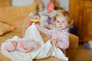 Adorable cute little toddler girl playing with doll. Happy healthy baby child having fun with role game, playing mother