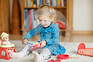 Adorable cute little toddler girl playing with doll. Happy healthy baby child having fun with role game, playing mother
