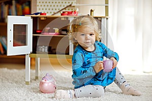 Adorable cute little toddler girl playing with toy kitchen Happy healthy baby child having fun with role game, playing