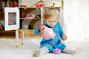 Adorable cute little toddler girl playing with toy kitchen Happy healthy baby child having fun with role game, playing