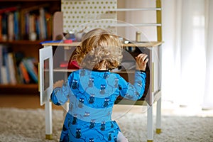 Adorable cute little toddler girl playing with toy kitchen Happy healthy baby child having fun with role game, playing