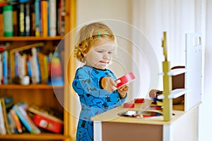 Adorable cute little toddler girl playing with toy kitchen Happy healthy baby child having fun with role game, playing