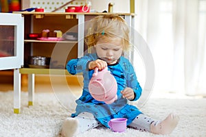 Adorable cute little toddler girl playing with toy kitchen Happy healthy baby child having fun with role game, playing