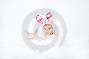 Adorable cute newborn baby girl in Easter bunny costume and ears. Lovely child playing with plush rabbit toy. Holiday