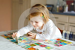 Adorable cute toddler girl playing picture card game at home or nursery. Happy healthy child training memory, thinking