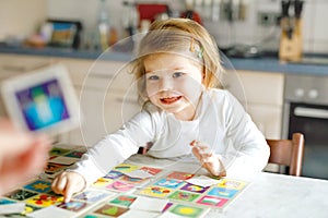 Adorable cute toddler girl playing picture card game with mother or father. Happy healthy child training memory
